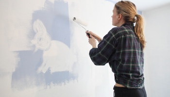woman painting wall white using a paint roller © RSPCA