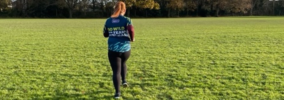 view of runner from behind wearing rspca sponsored t-shirt running in a field