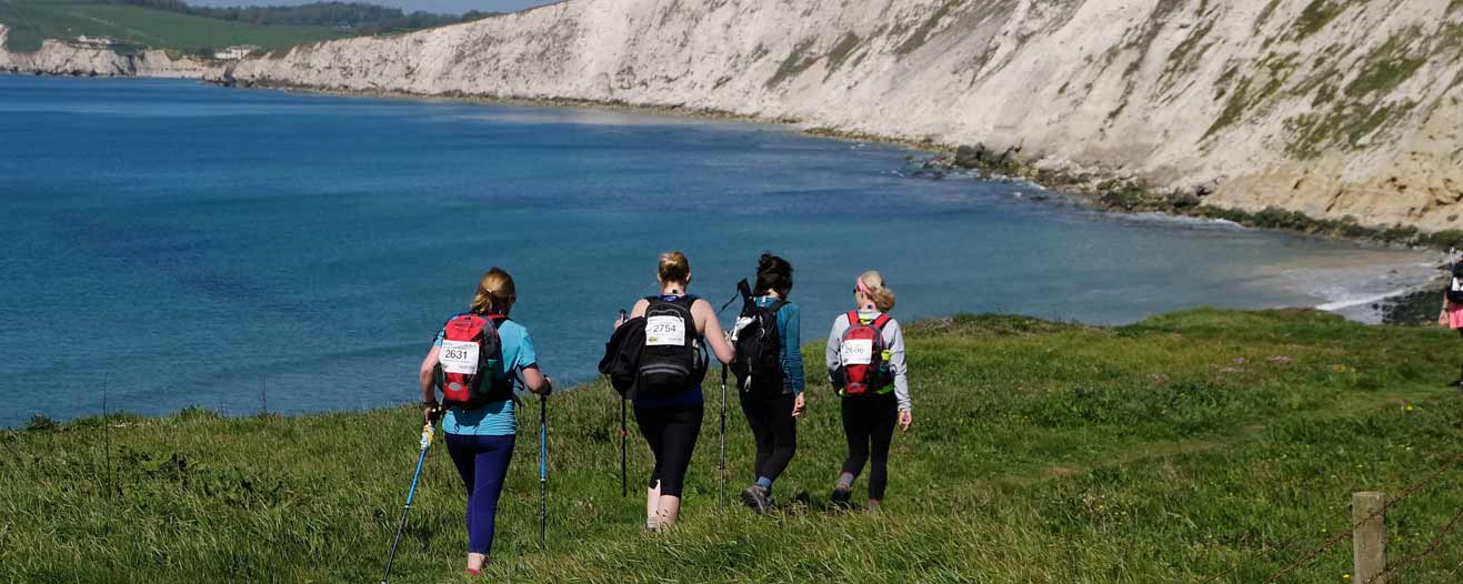 Three trekkers walking along the coastline on the Isle of Wight.