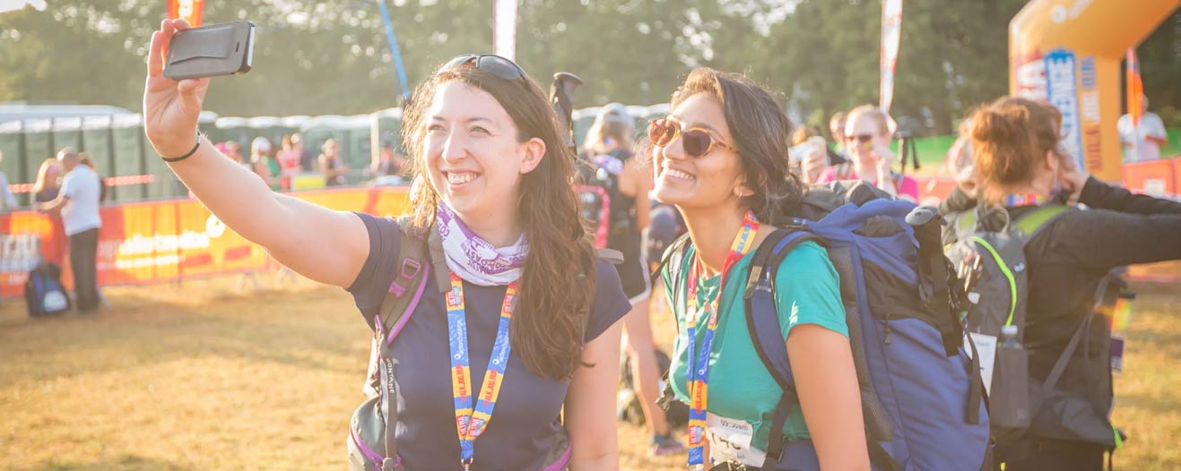 Two trekking fundraisers taking a selfie to show off their finisher medals.