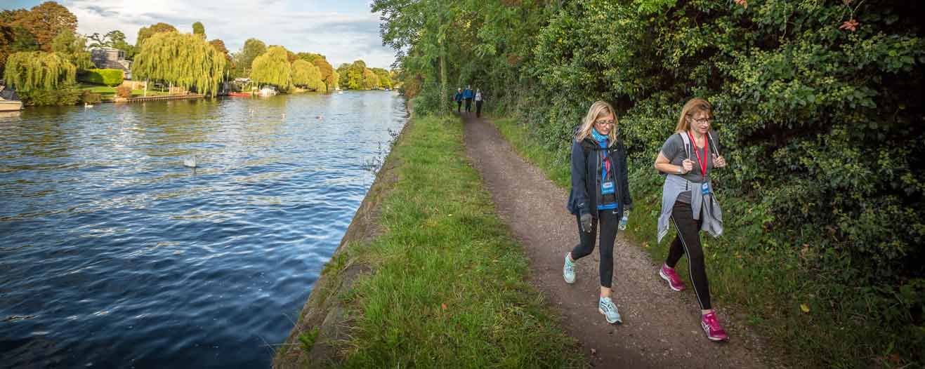 Two female charity fundraisers walking along the Thames towpath.
