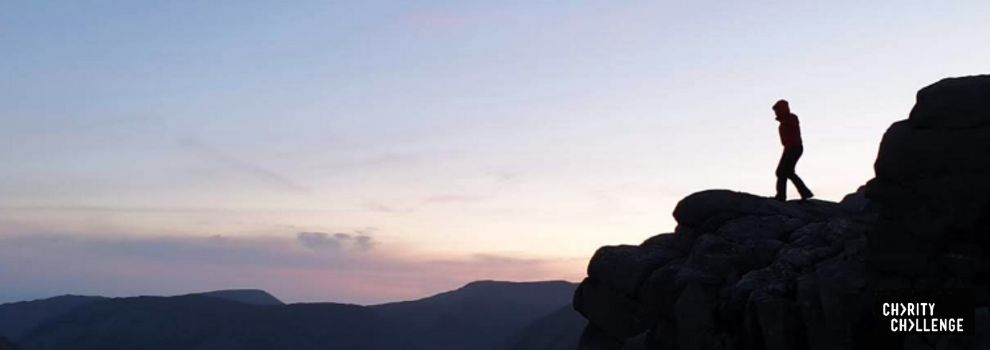 hiker on top of a mountain ledge at sunrise