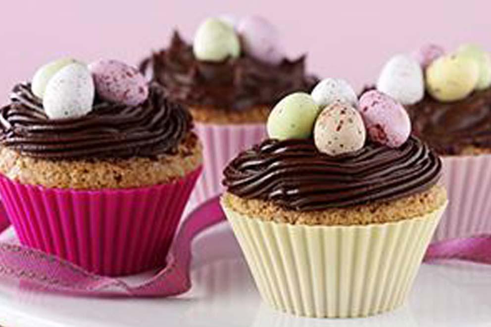 Four Easter themed cupcakes decorated with chocolate icing and mini-eggs.