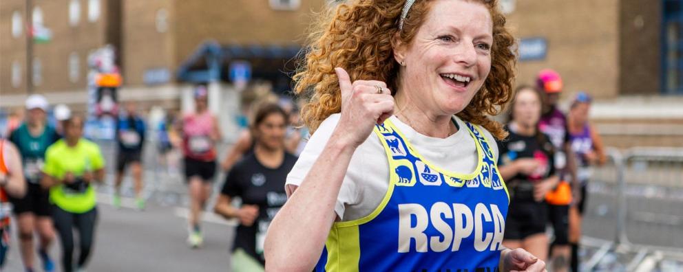 A woman with curly red hair running in a race, she is smiling