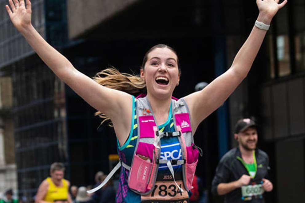 Happy fundraiser with arms in the air smiling as she's running.