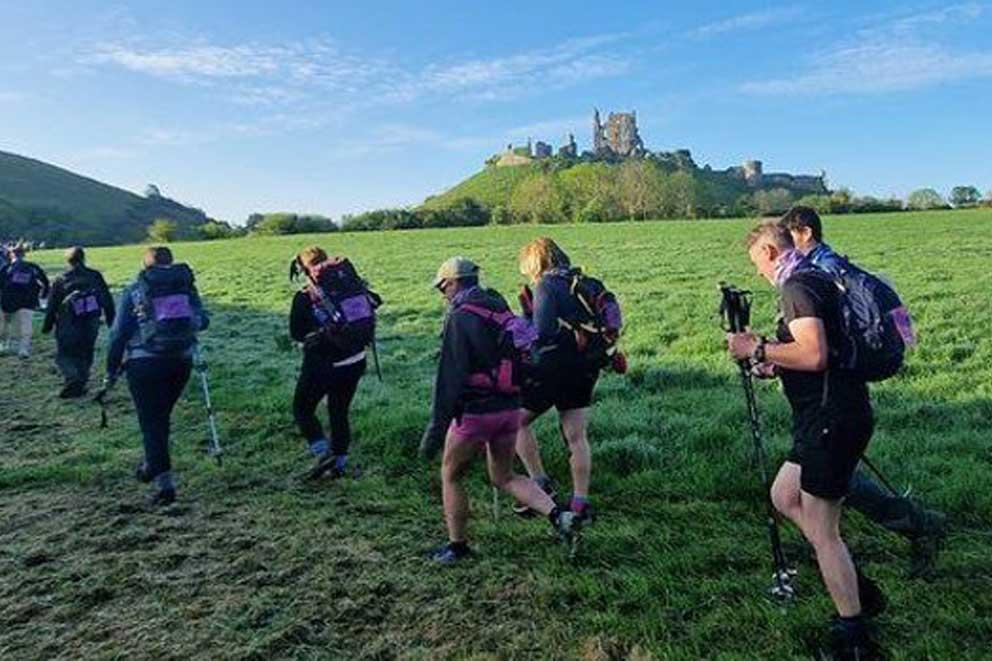 Fundraisers taking part in organise trek walking towards Corfe Castle in Dorset.