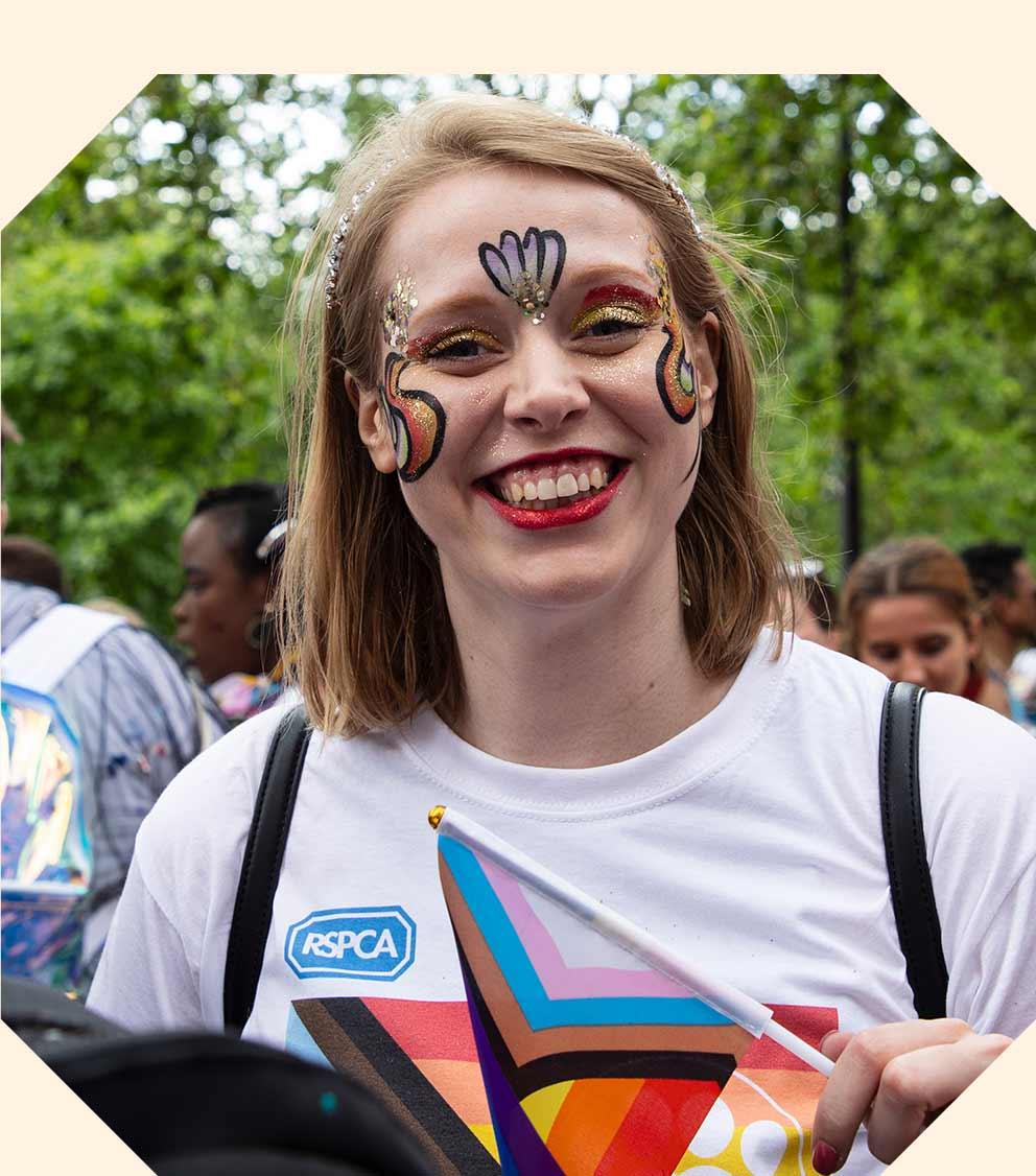 A woman with her face painted looks into the camera and smiles