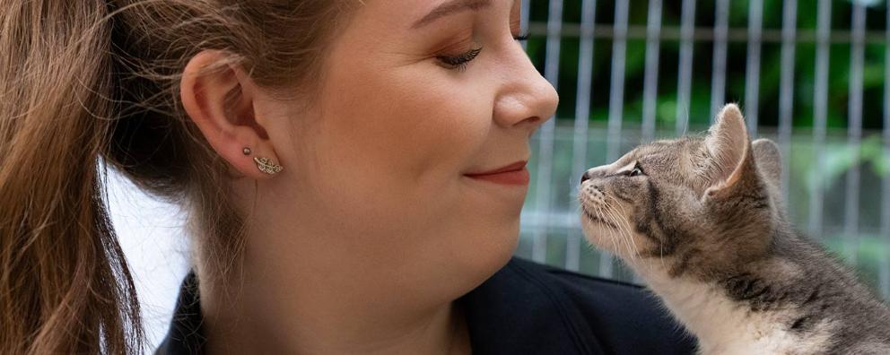 Young woman smiling at a cat who is looking back at her lovingly.