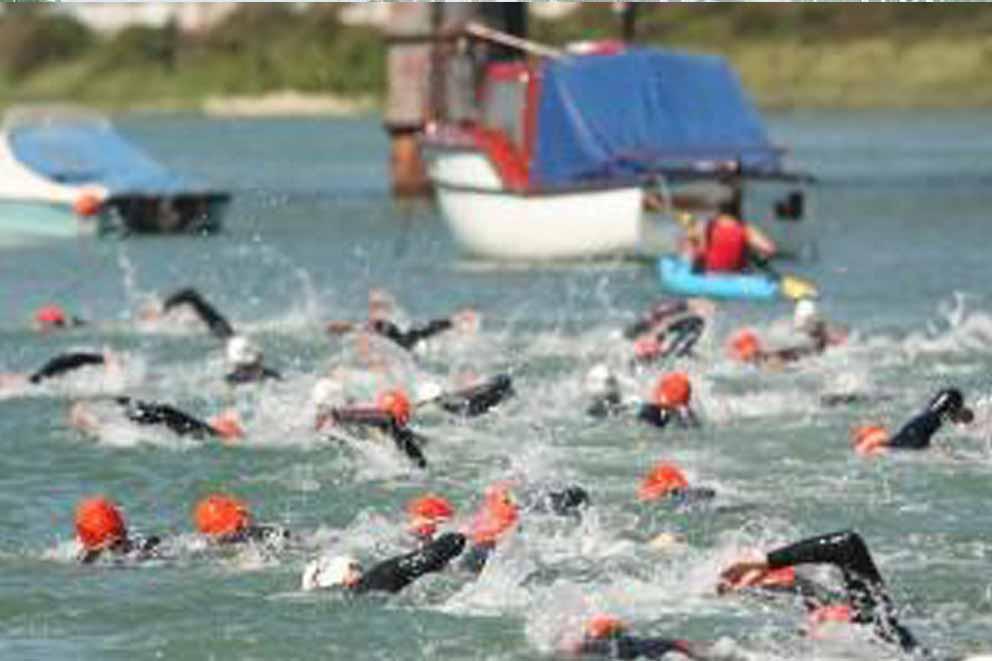 Swimmers swimming in a swimming fundraise event outdoors.