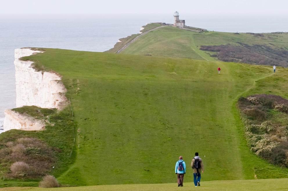 Two trekkers walking the South Downs way towards Beachy Head in Sussex.